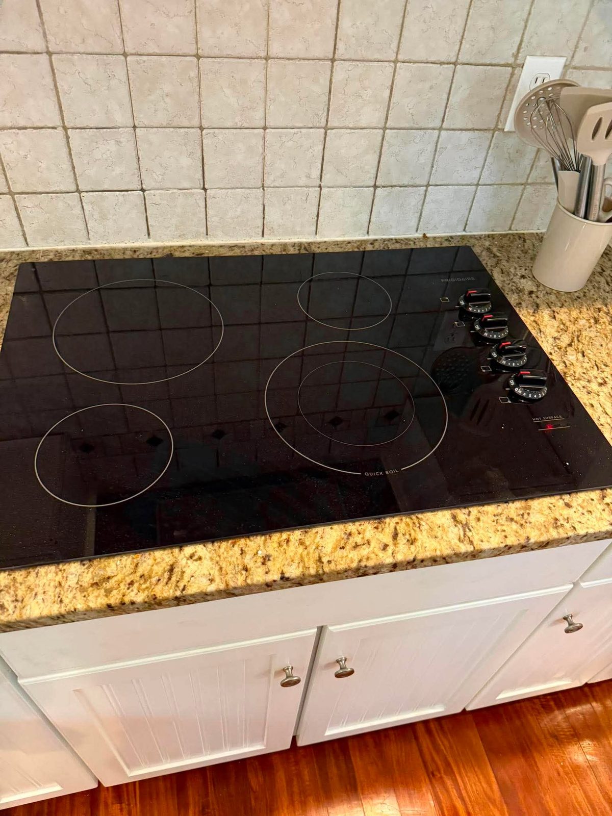 Black electric cooktop set into a granite counter
