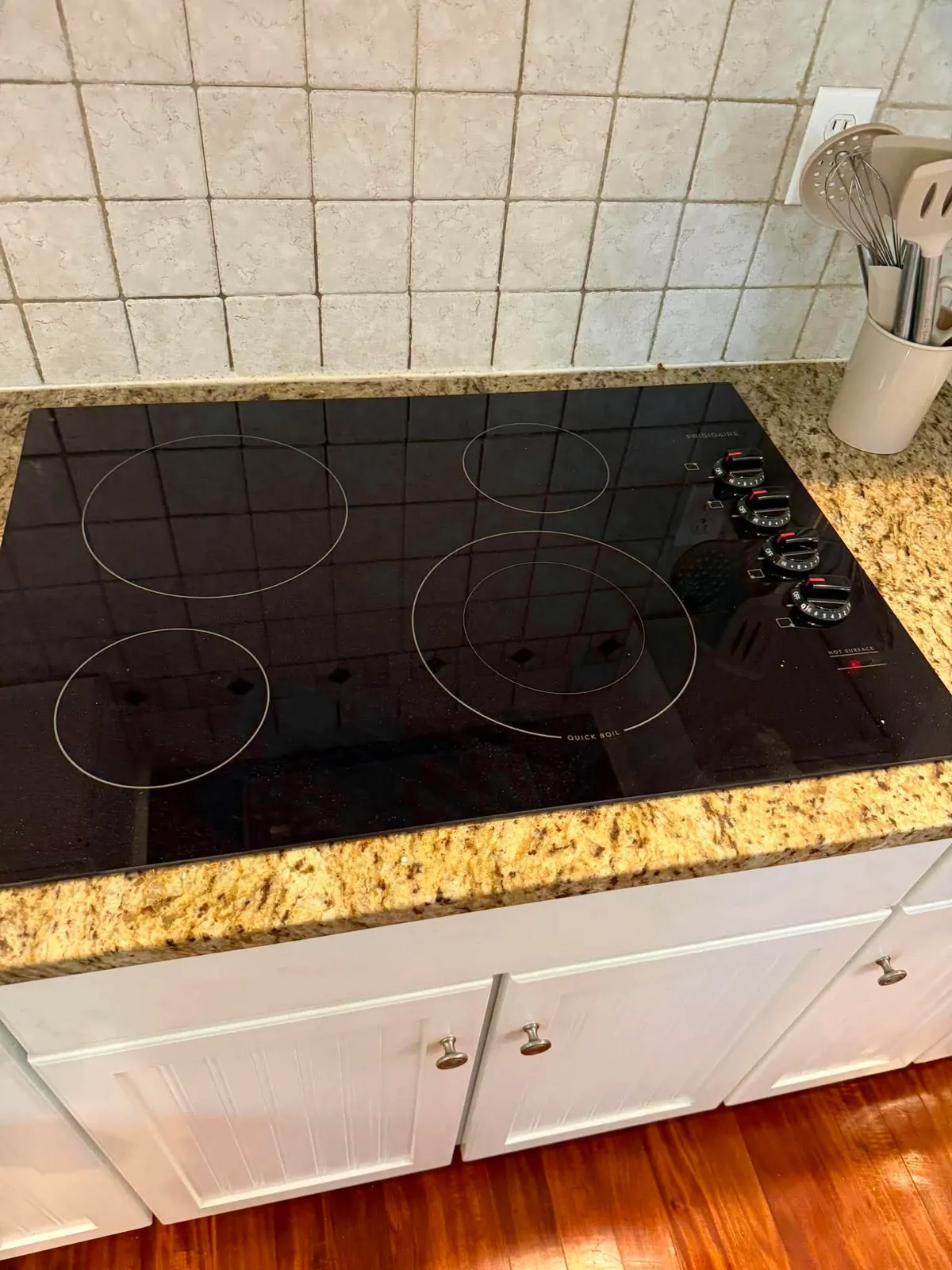 Black electric cooktop set into a granite counter