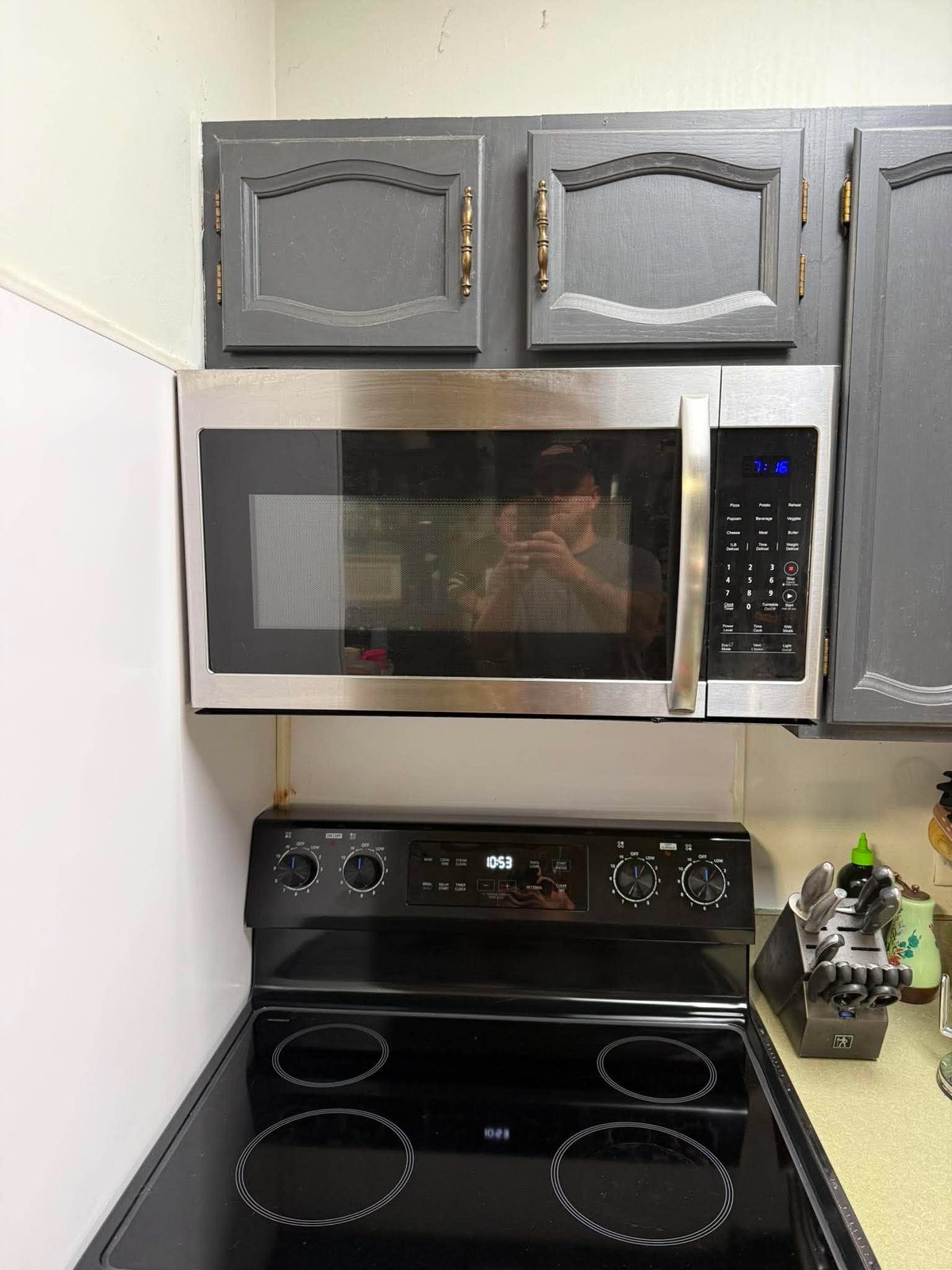 Stainless over-range microwave mounted above a black range