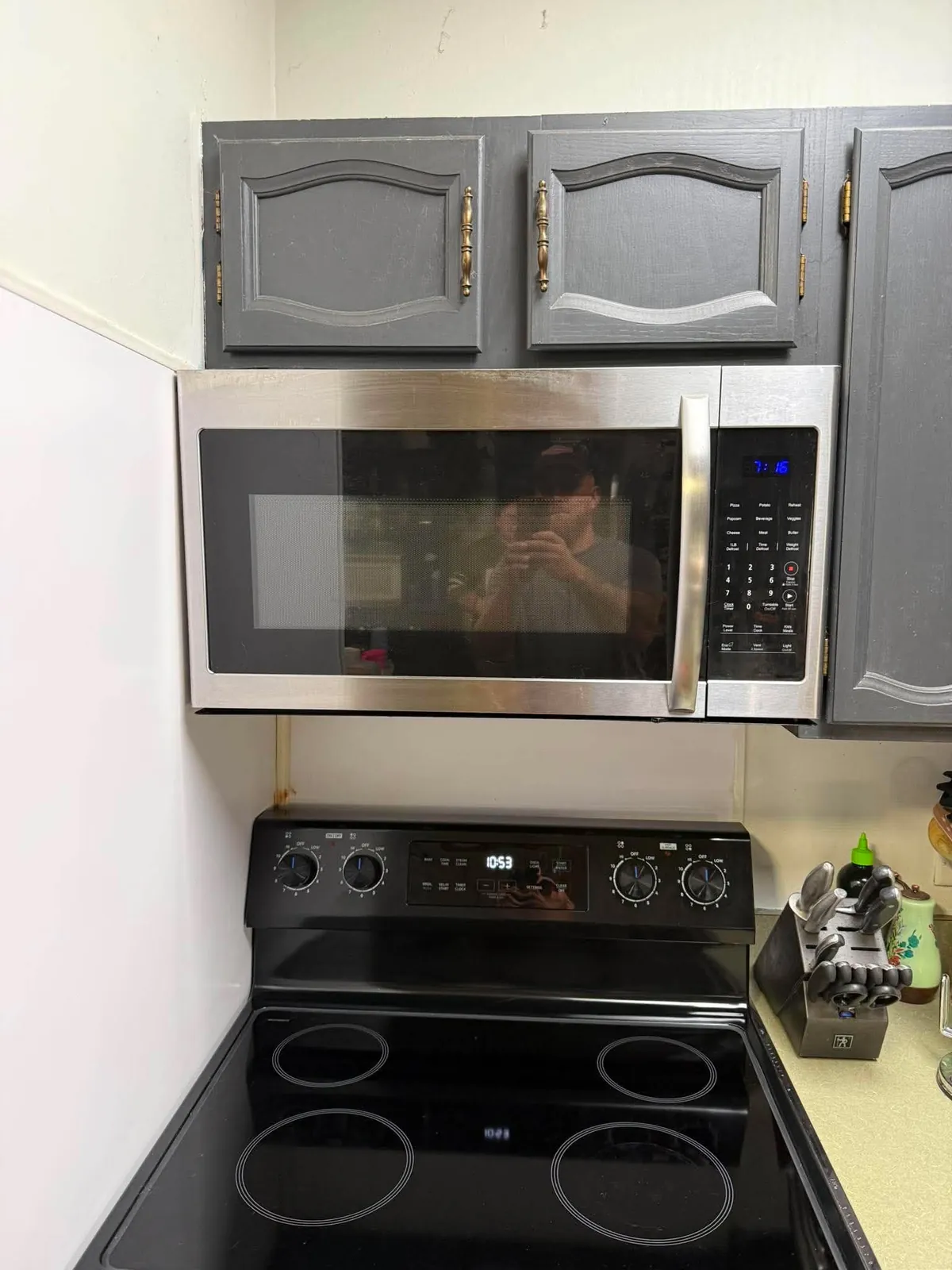 Stainless over-range microwave mounted above a black range