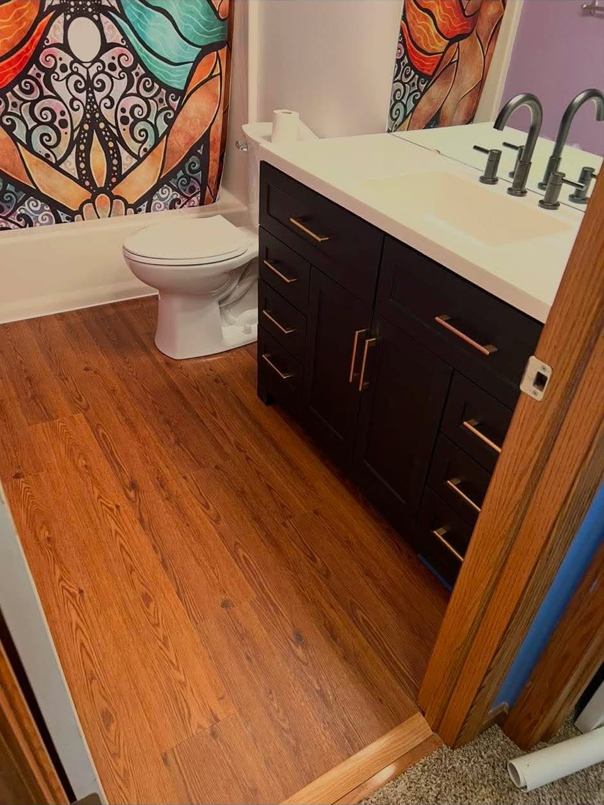 Dark espresso vanity with a wood-look plank floor and new toilet