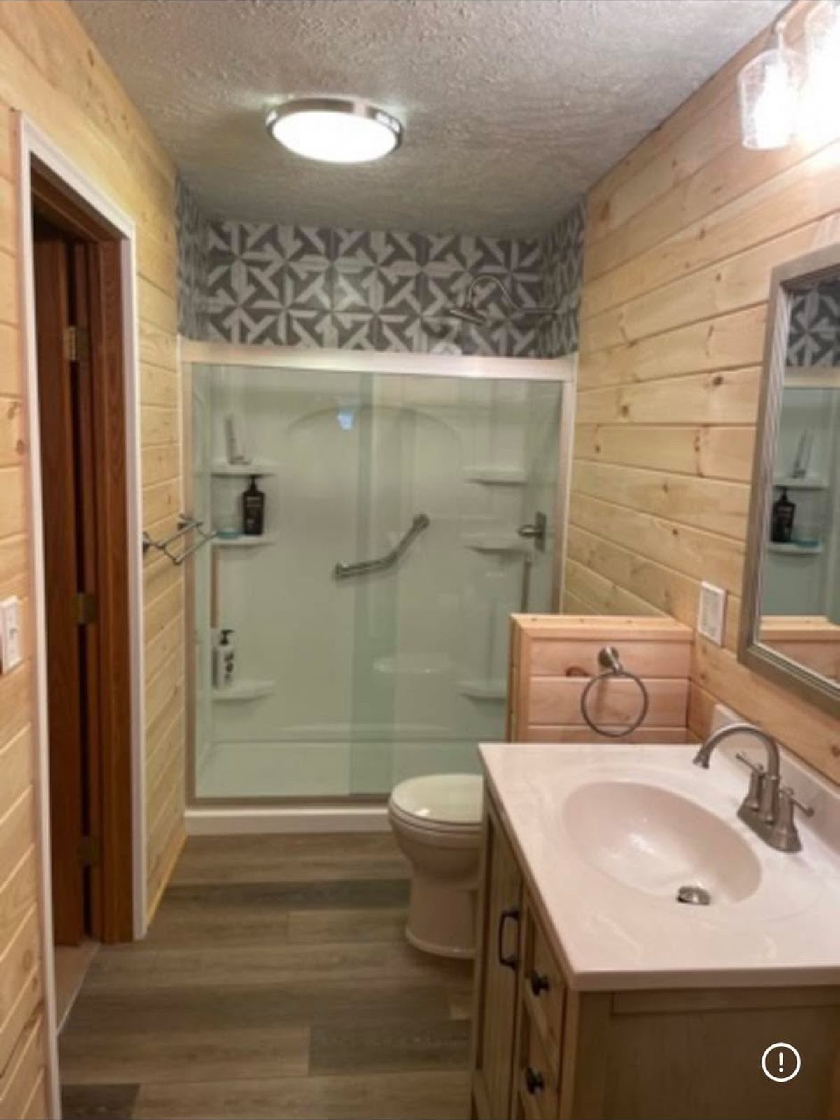 Glass walk-in shower with a grab bar beside a vanity
