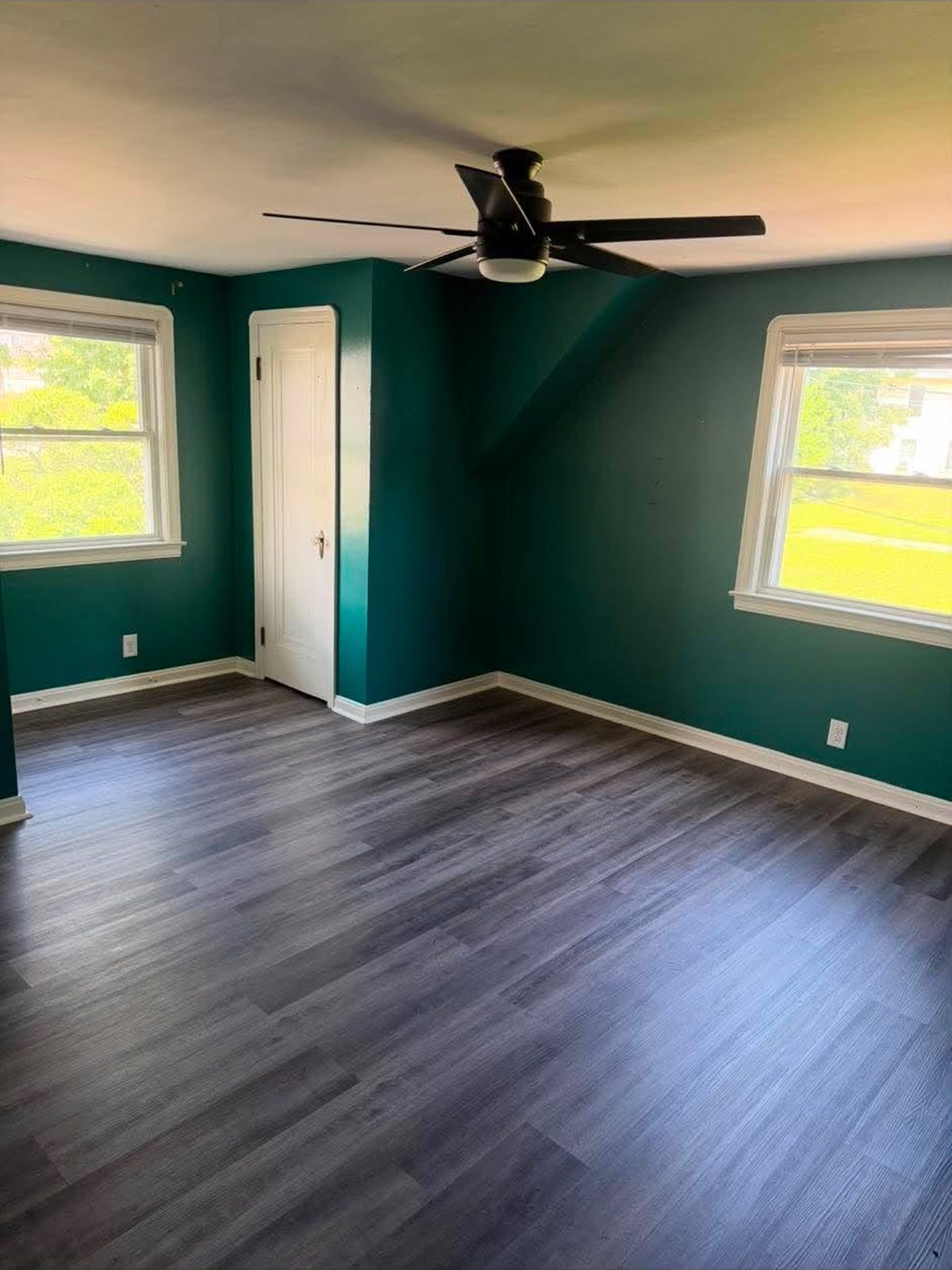 Grey plank flooring in a bedroom with dark green walls