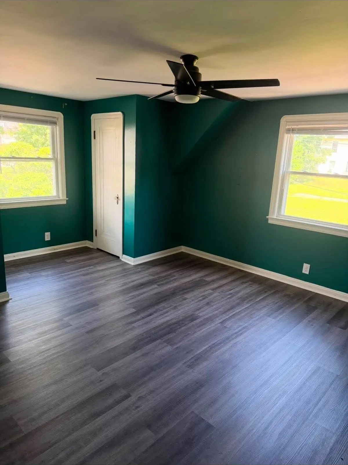 Grey plank flooring in a bedroom with dark green walls