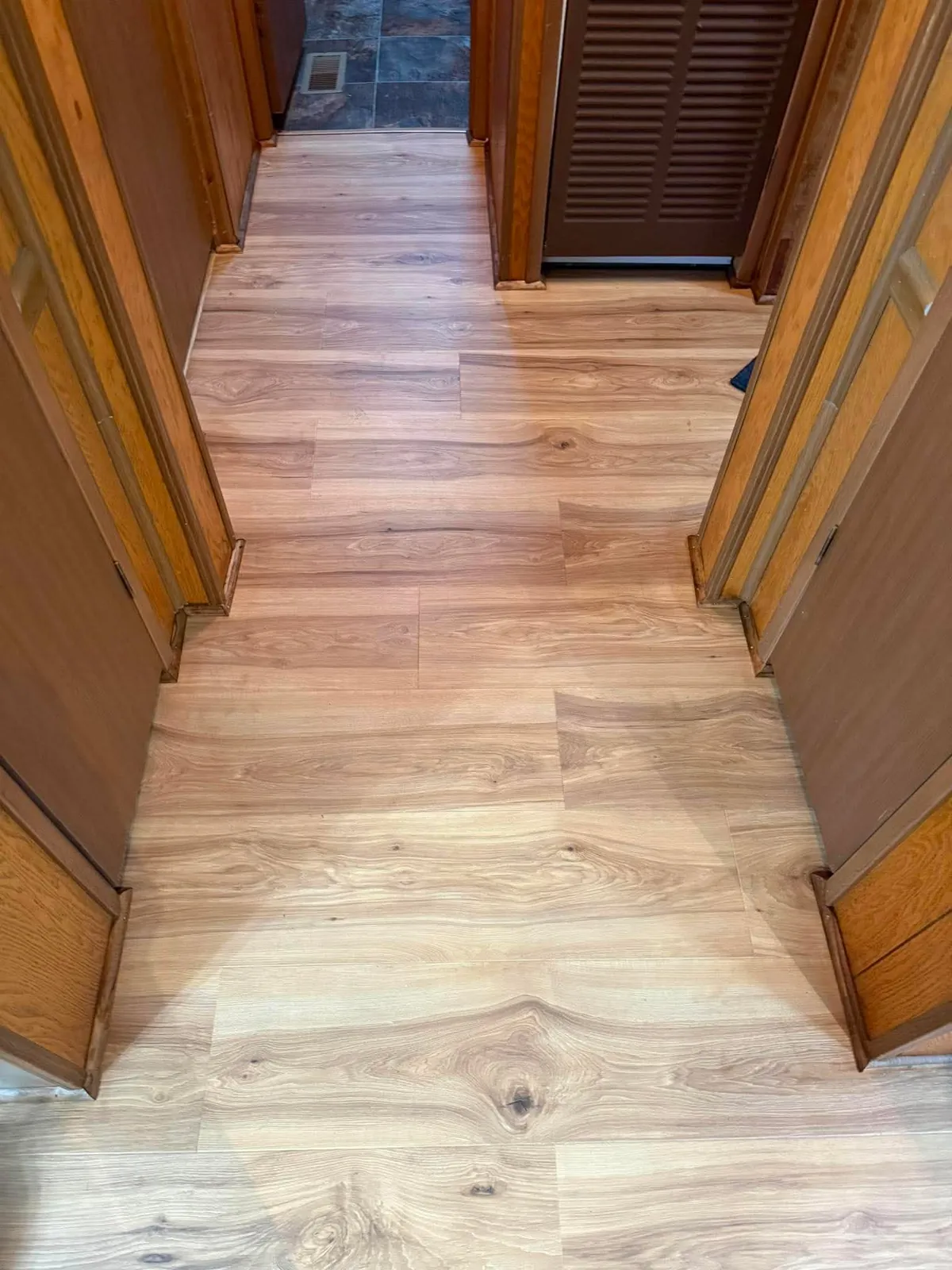 Plank flooring running down a hallway between wood doors