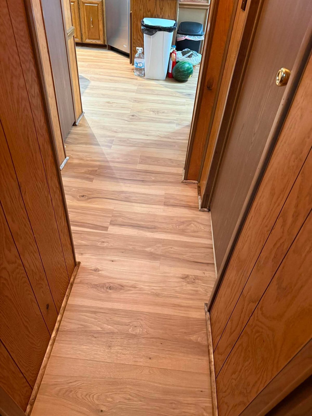 Plank flooring running from a hallway through to a kitchen