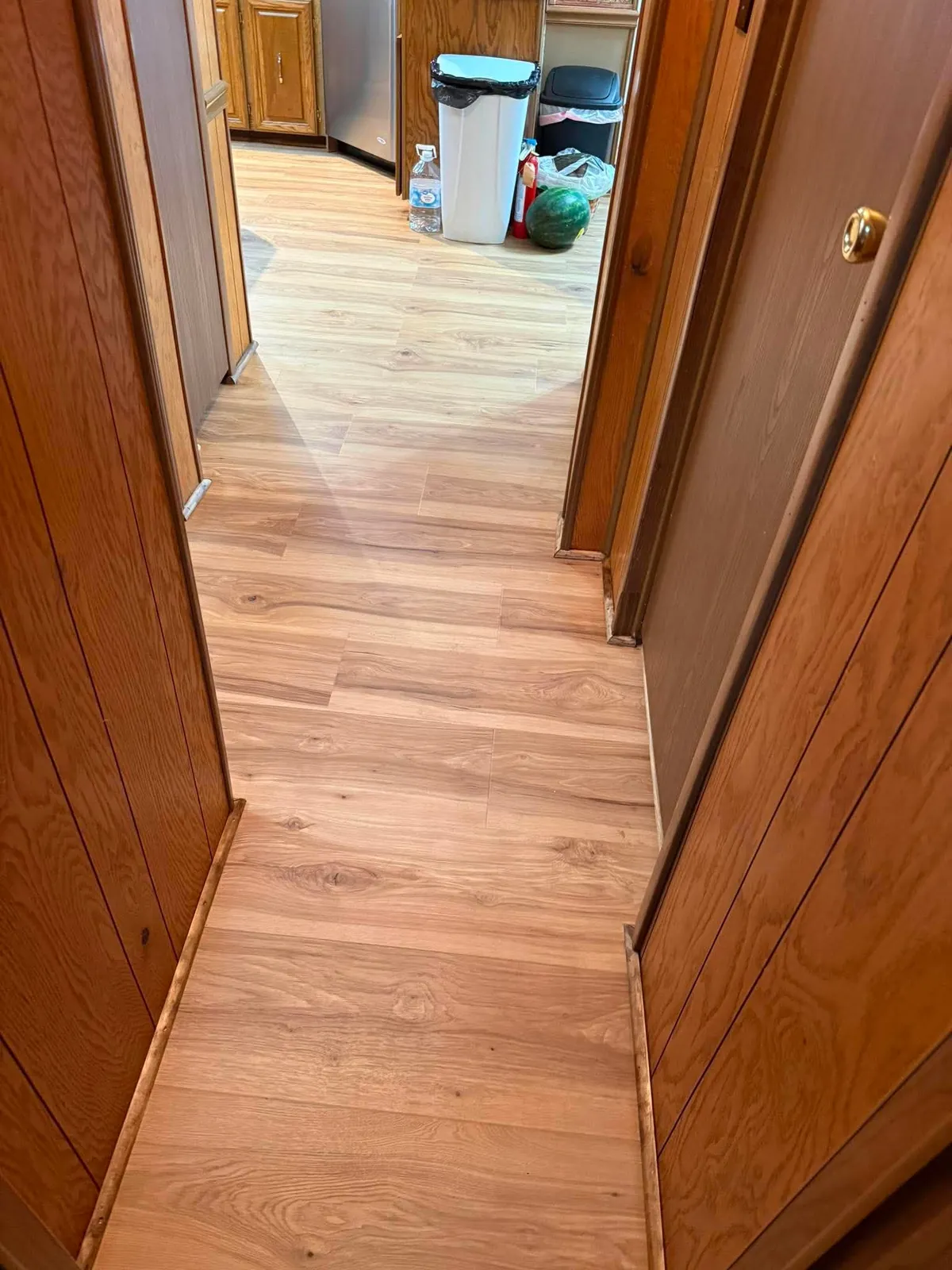 Plank flooring running from a hallway through to a kitchen
