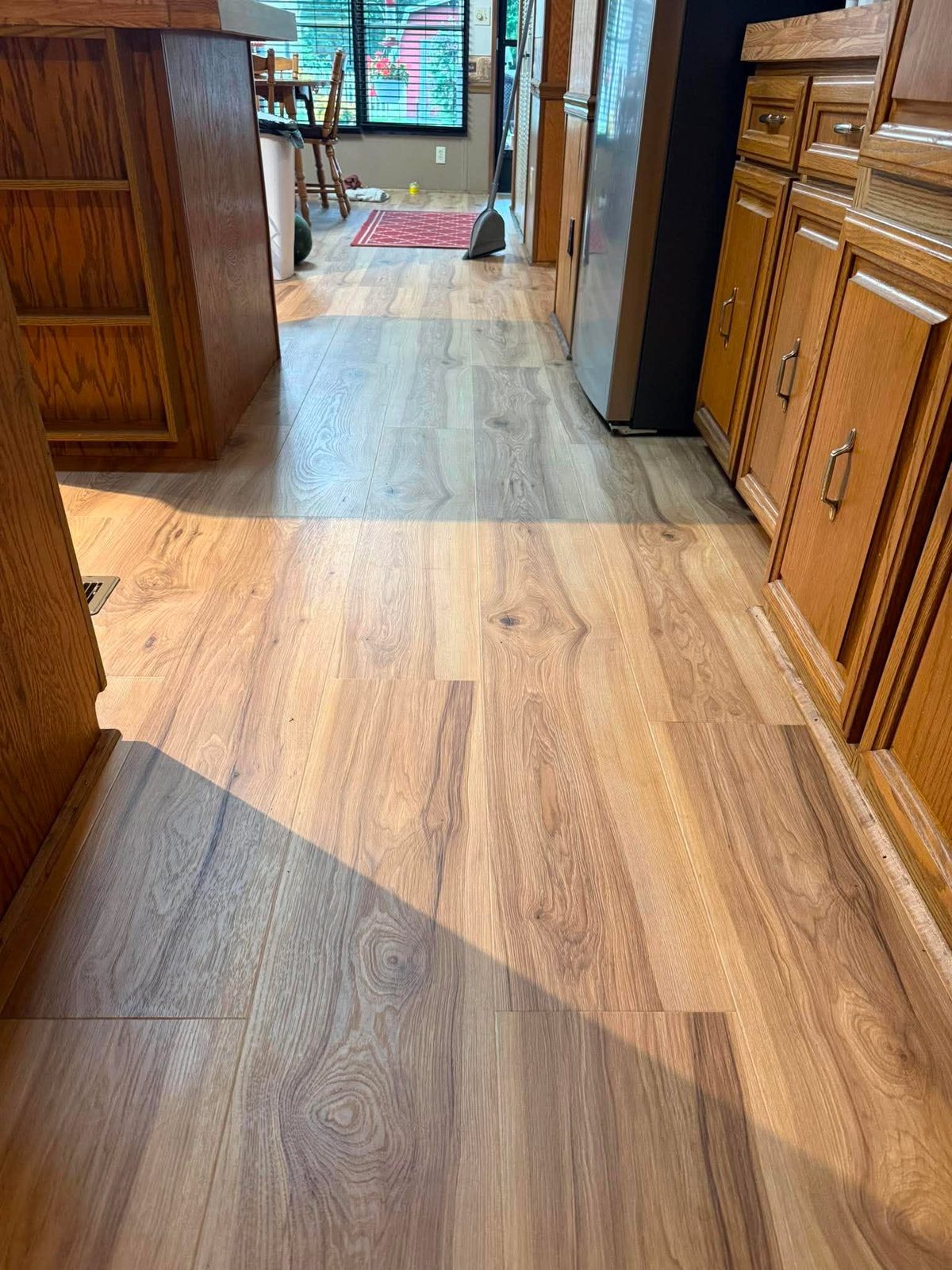 Wide plank flooring running through a kitchen past oak cabinets