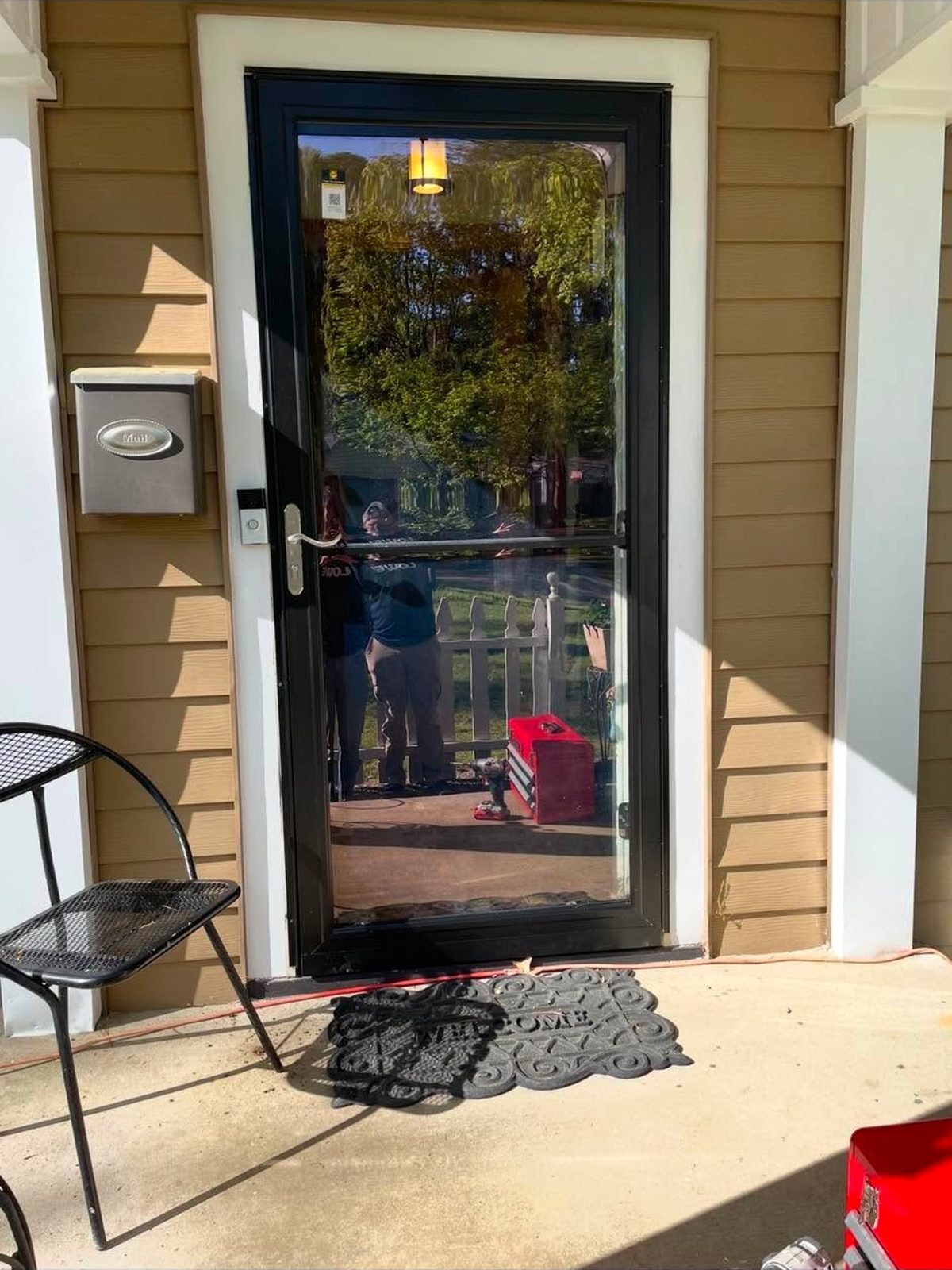 Black full-view storm door installed on a covered porch