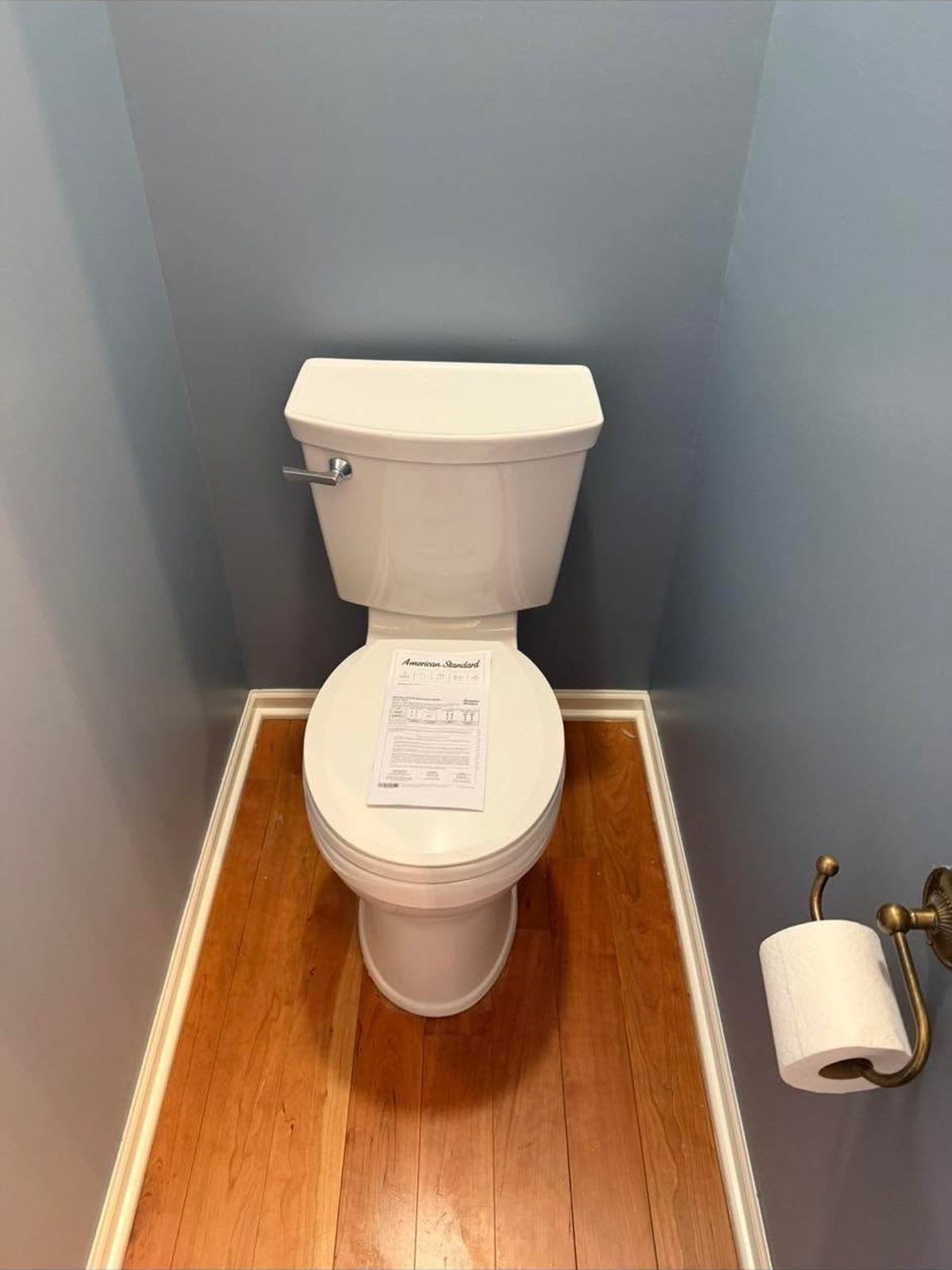 New white toilet installed on a hardwood floor