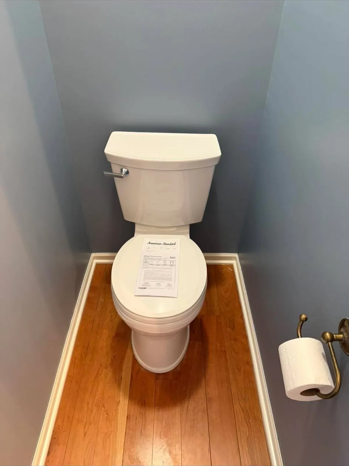 New white toilet installed on a hardwood floor