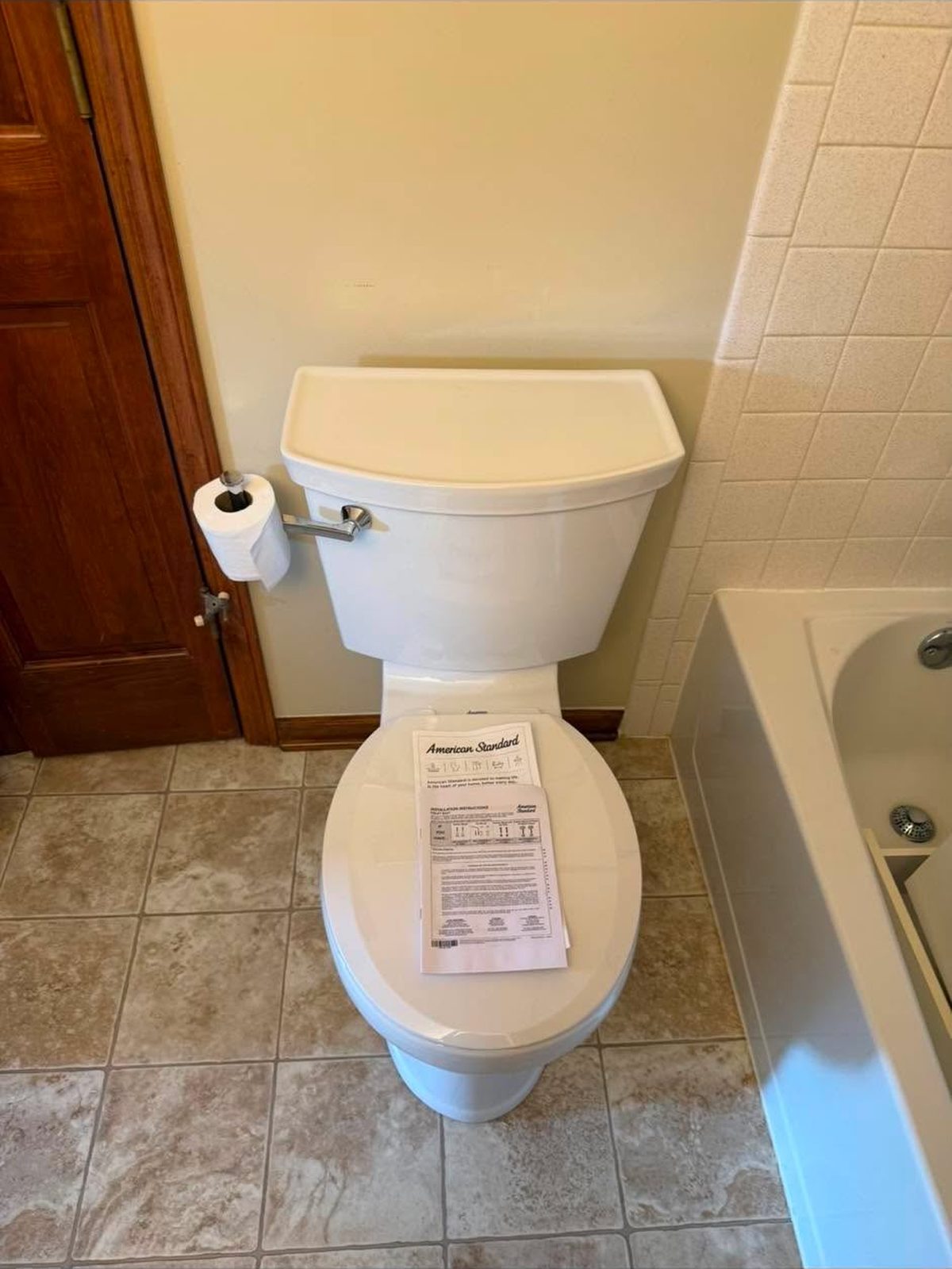 New white toilet installed beside a tub alcove